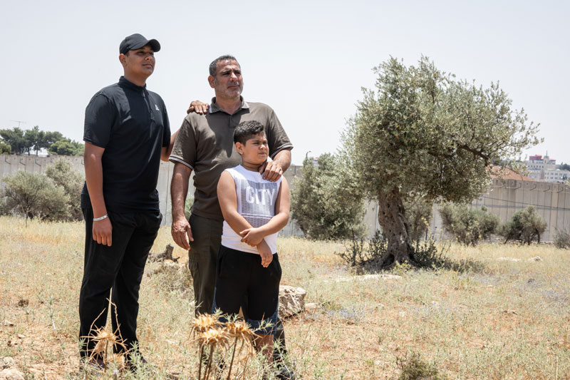 Sa&apos;ed and his sons Mahmoud and Ahmad in their garden, which the Wall separates from Bethlehem