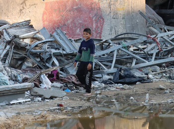 A boy passing by a crater near Kamal Adwan Hospital. Photo by OCHA/Themba Linden