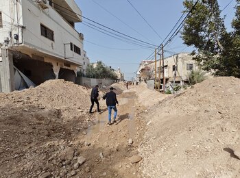 פלסטינים הולכים על מה שנותר מכביש שנהרס בדחפורים בעיר ג'נין, לאחר מבצע שניהלו כוחות ישראליים בעיר ב-11 במרס 2025. צילום: עיריית ג'נין