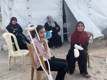 Girls sitting at a field hospital run by International Medical Corps after receiving medical treatment for injuries sustained in a 26 May strike on a site for displaced people in Rafah. Photo by OCHA/Yasmina Guerda, 27 May 2024