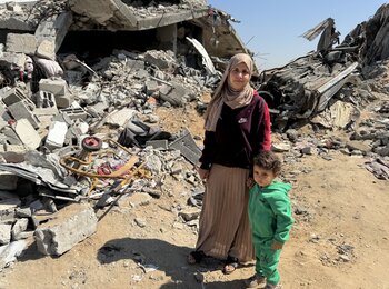 Yasmeen and her son stand amid the rubble of their destroyed home in Gaza, where renewed airstrikes and aid restrictions have deepened the humanitarian crisis. Photo: OCHA/Olga Cherevko