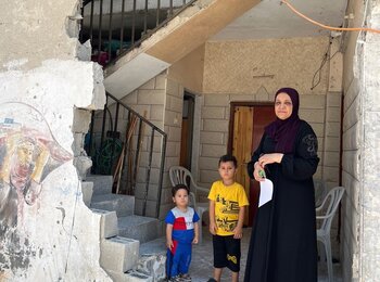 A Palestinian woman with her two grandchildren next to their home in Tulkarm Refugee Camp, after an explosion during an operation by Israeli forces on 22 July. The ground floor is now uninhabitable, while the upper floors, where the children live, are damaged but liveable. Photo by OCHA, 24 July 2024