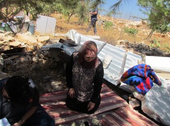 A Palestinian mother of four, resident of Jourat al Khiel, sitting on the belongings of her family following the demolition of their home by the Israeli authorities on 16 August 2016