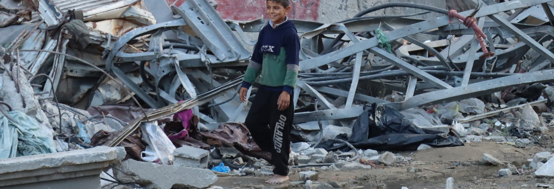 A boy passing by a crater near Kamal Adwan Hospital. Photo by OCHA/Themba Linden