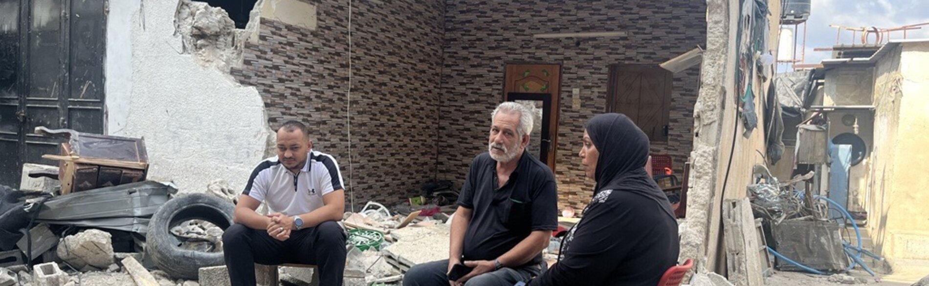 A displaced Palestinian family sitting amid the rubble of their destroyed home in Tulkarm refugee camp, following an Israeli operation. Photo by OCHA, 7 September 2024 