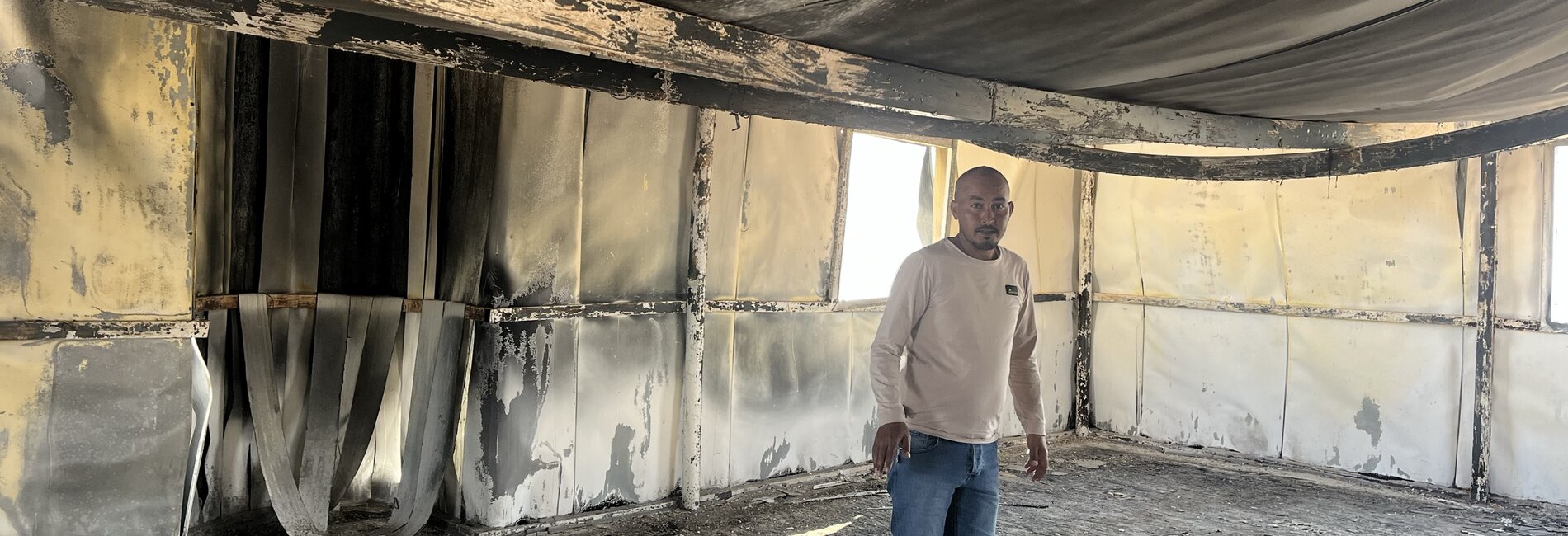 Suliman Mlihat, a herder living in Al Mu'arrajat East Bedouin community, in Jericho, standing in the community mosque set on fire by Israeli settlers on 2 February 2025. His tractor, used to transport water, was also burnt in the attack. Photo by OCHA.