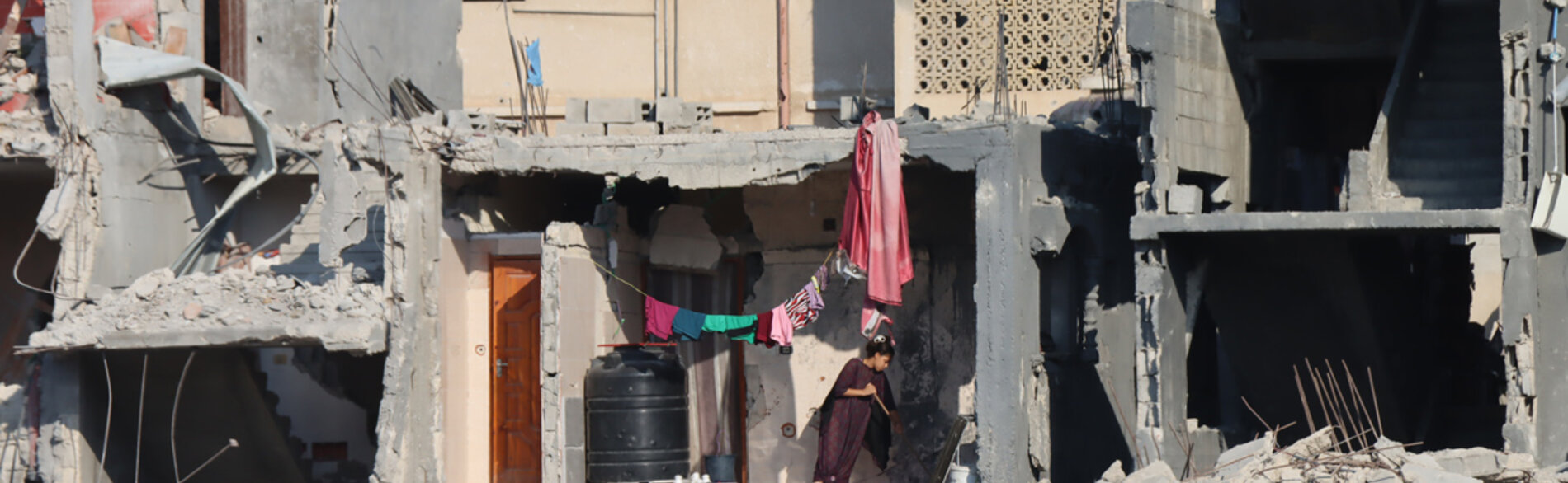 A Palestinian girl wiping the floor of a heavily damaged house in Abasan Al Kabira, area of Khan Younis. Photo by OCHA/Themba Linden, 7 September 2024