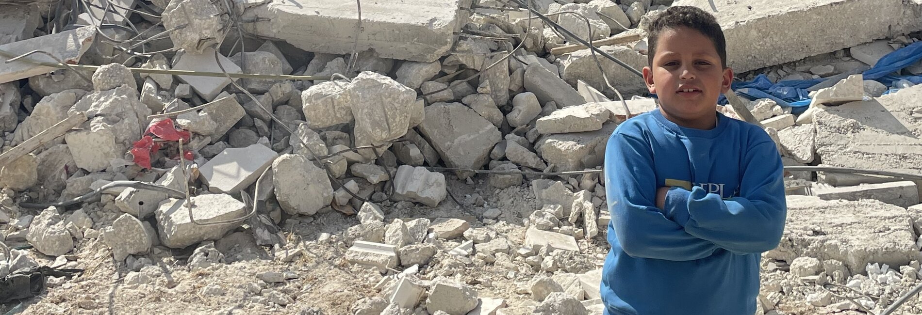 A Palestinian boy standing in front of his house that was under construction but was demolished by Israeli forces for lack of an Israeli-issued building permit, in Beit Ummar. Photo by OCHA, 14 November 2024. 