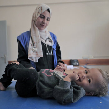 May 26, 2024, Rafah: A staff member from the UNRWA Health Team at the Tel Al-Sultan Health Center in Rafah area conducts a medical examination for a displaced child.© 2024 UNRWA Photo by Mohammed Hinnawi